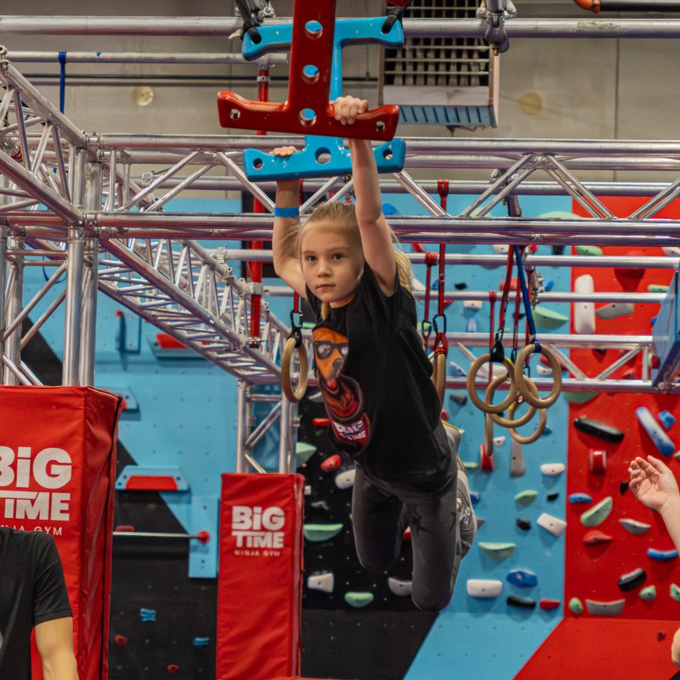 Ninja gym athlete holding a climbing position during kids classes