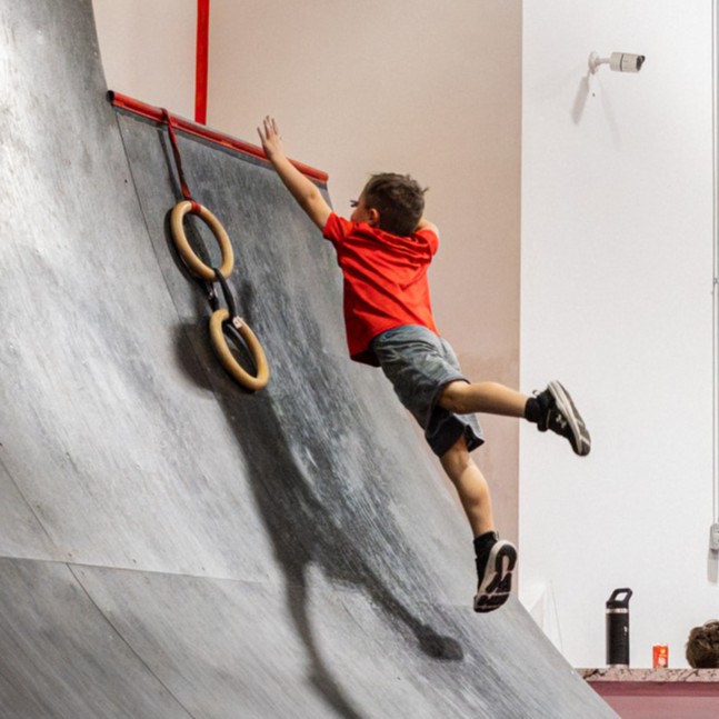Kids jumping off the warped wall obstacle during a birthday party